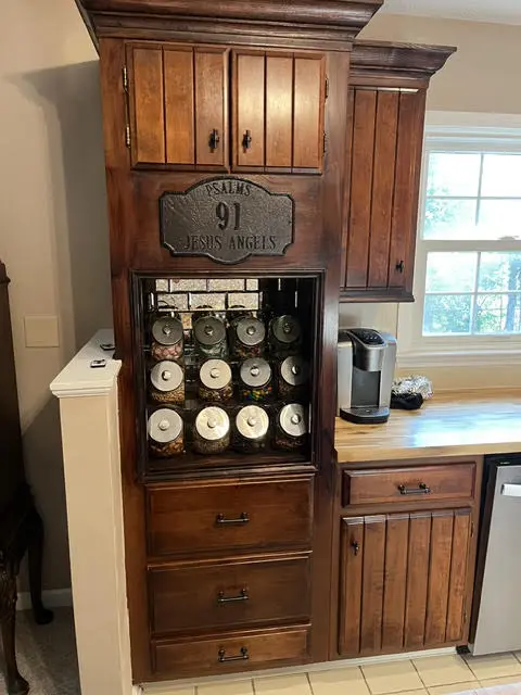 The same corner after: a full-height stained hutch with a drawer bank, an open middle shelf holding jars and a coffee machine, and cabinets above.