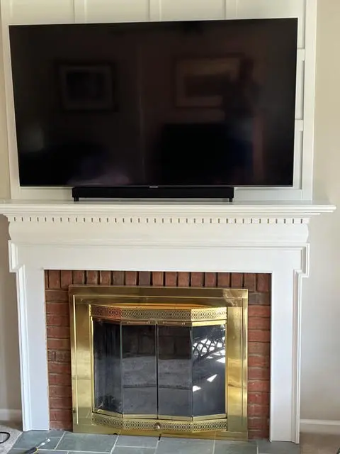 Fireplace before: red brick surround with brass-framed glass doors under a white painted mantel.