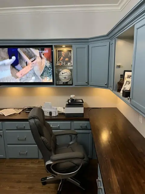 The finished built-ins: blue-grey painted cabinets, walnut counter tops, lit shelving, and a wall-mounted television.