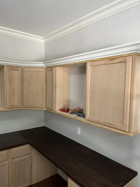 Office built-ins mid-build: unfinished oak cabinet boxes and a bare counter run, hung but not faced or painted.