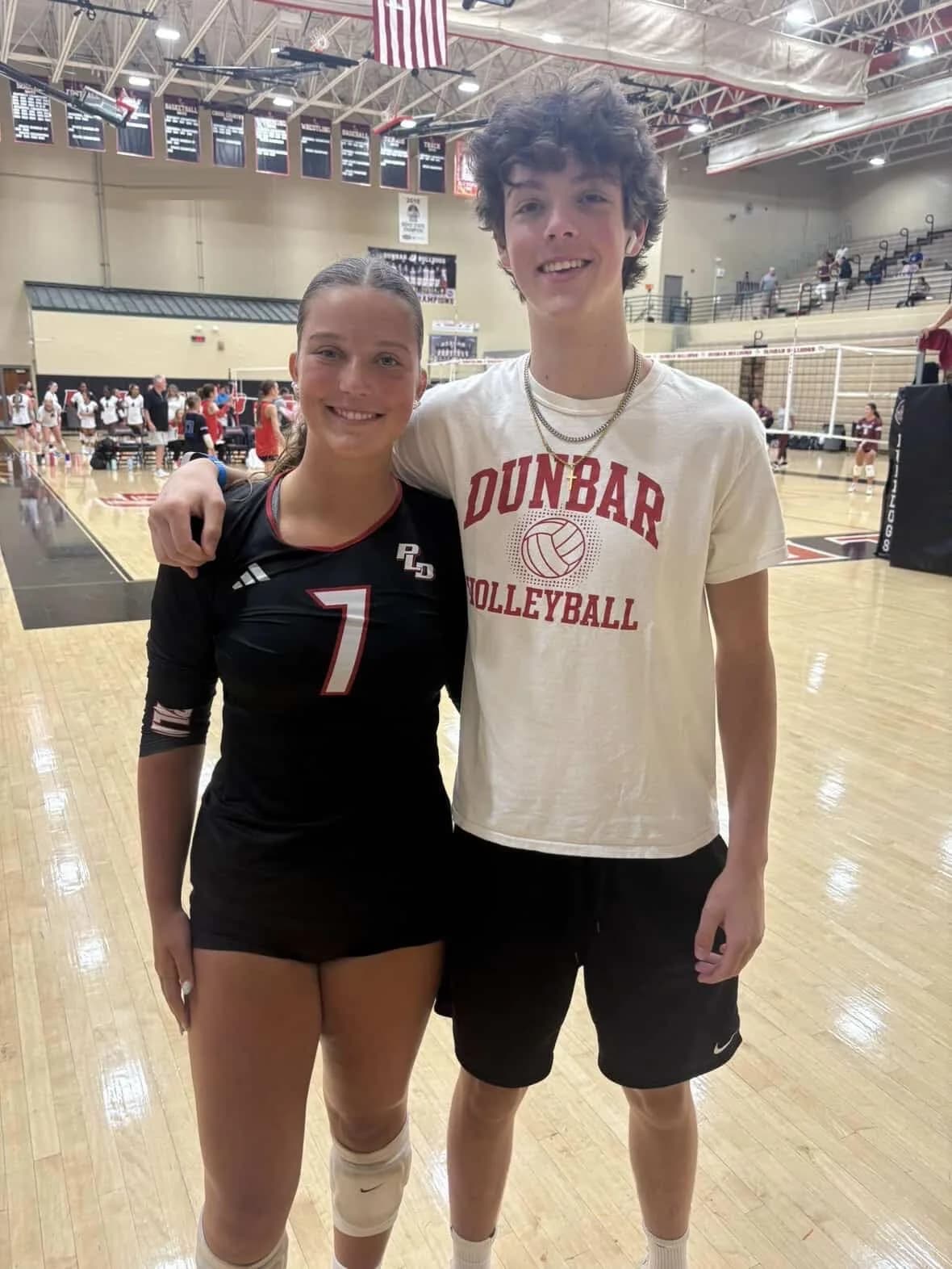 Sadie in her volleyball uniform with her brother Everett's arm around her shoulders, in a school gym.