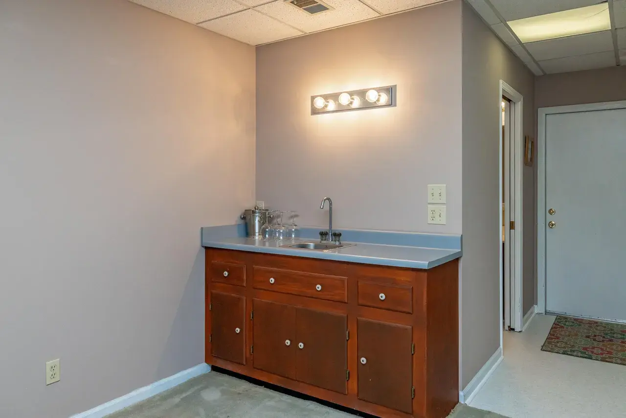 The wet bar before: a single base cabinet with a sink against a bare wall, under a strip light.