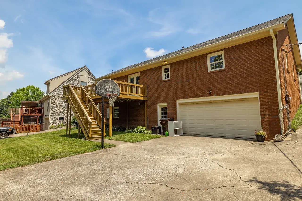 The original deck seen from the yard, raised above a walk-out basement with wood stairs down to the drive.