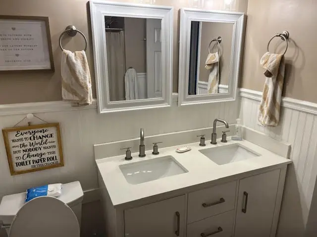 The new vanity: two undermount sinks in a white top, two framed mirrors, and two light bars.