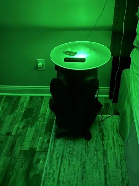 The same side table in a dark room, lit from beneath by a green LED ring.
