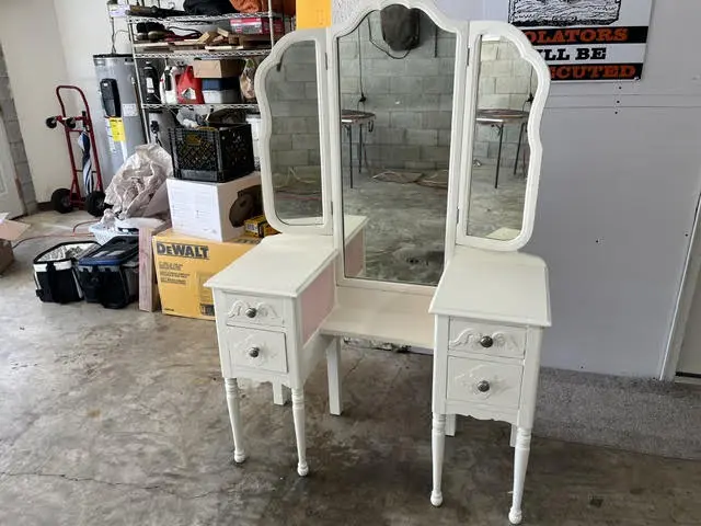 An antique dressing table repainted white, with its three-panel mirror reassembled.
