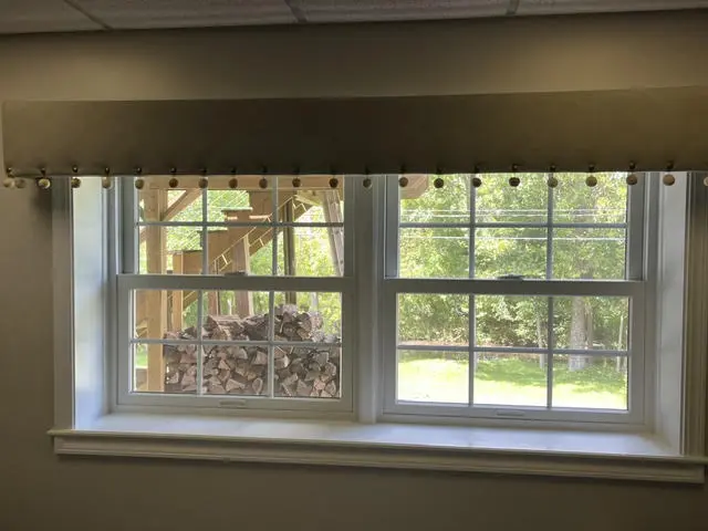 A window with a new rod and a pleated valance fitted above the frame.